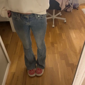 True Religion Joey Low Rise Flare Jeans - Säljer ett par ljusblå True Religion Joey jeans med låg midja och flare-ben. Klassisk femficksmodell med snygga detaljer på bakfickorna och silverfärgade knappar. 