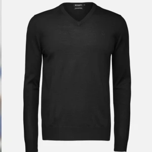 Svartgrå v-ringad tröja Tiger of Sweden - Svartgrå v-ringad tröja från Tiger of Sweden, tillverkad i fin italiensk ull.  Diskret logga på bröstet. Mycket bra skick! Nypris 1200