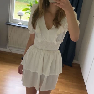 Vit volangklänning från Gina Tricot - Supersöt vit kortklänning från Gina med volangdetaljer och v-ringning. Storlek xs och bara använd en gång🤗