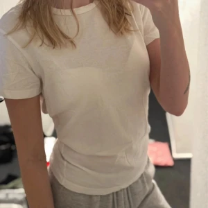 Vit t-shirt från 157 - En klassisk vit t-shirt från 157 i 100% bomull. T-shirten har rund halsringning och korta ärmar, perfekt för en enkel och clean look. Passformen är normal och materialet känns mjukt mot huden.