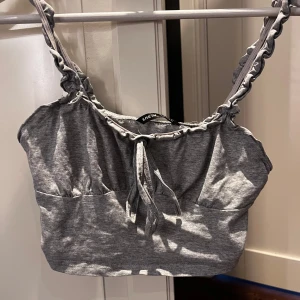 Grå croppad linnetopp från SHEIN - Säljer en grå croppad linnetopp från SHEIN med twistade axelband och knytning framtill. Perfekt för varma dagar och enkel att matcha med jeans eller kjol.