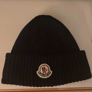 Svart ribbad mössa från Moncler - Säljer en mörkblå ribbstickad mössa från Moncler. Nyskick använd 5 ggr kanske säljer pga att jag inte är möss fantast. 