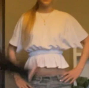 Vit croppad blus med volang - Säljers en vit croppad blus med volang nertill och vida korta ärmar. 