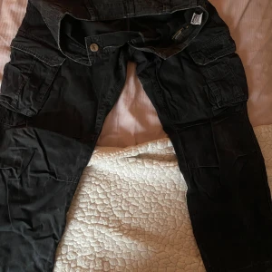 Svarta vintage  cargopants från GASP INC - Svarta vintage cargopants från GASP INC med flera stora fickor på sidorna och bak. Byxorna har en klassisk cargomodell med normal passform och robust bomullsmaterial.