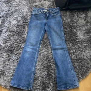Blå bootcut jeans från Perfect Jeans - Säljer ett par klassiska blå bootcut jeans från Gina tricot. Jeansen har normal passform upptill och utsvängda ben, fem fickor och stängs med dragkedja och knapp.