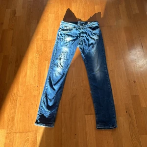 Blå Replay jeans slim fit - Säljer ett par blå Replay jeans med slim passform. Klassisk femficksmodell med snygga slitningar och raka ben. Jeansen har tydlig Replay-lapp bak i midjan och är perfekta för en avslappnad stil.