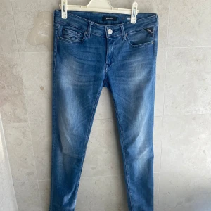 Blå Replay jeansbyxor - Säljer ett par klassiska blå jeans från Replay med fem fickor . Byxorna har normal passform och raka ben, med dragkedja och knapp i midjan. Perfekta till vardags och enkla att matcha med olika stilar.