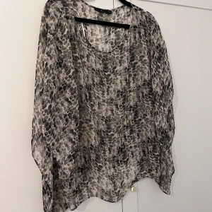 Svartvit blus med abstrakt mönster - Säljer en luftig och transparent blus i svart och vitt med abstrakt prickigt mönster. 