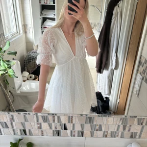 Vit kortklänning med puffärm från Gina Tricot - Supersöt vit kortklänning från Gina Tricot med puffiga, genomskinliga ärmar och prickigt mönster. Djup v-ringning och lätt volang i kjolen. Perfekt till studenten! 🌸