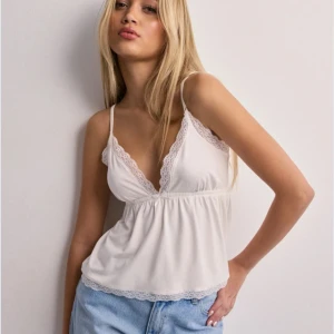 Vit babydoll topp från Nelly - Nypris: 250kr. Säljer en söt vit babydoll topp från Nelly. Nyskick (endast provad på en gång) Den är slutsåld och har varit det länge. Toppen har fina spetsdetaljer längs urringning och nederkant, samt en lätt rynkad midja för. Perfekt till sommaren!