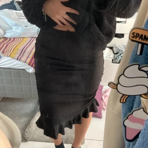 Figurnära svart kjol med volanger  - Supersöt tight knälång kjol med volanger längst ner. Den går att bära som hög och Lågmidjade och är väldigt stretchig. Går både att klä upp och ner! Storleken fungerar både som en XS och S. Knappt använd.  Hör av er om ni har några frågor💕