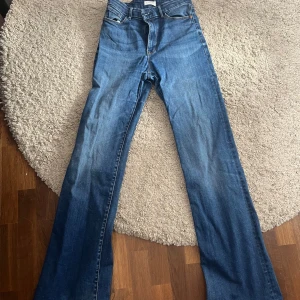 Blå bootcut jeans - Säljer ett par klassiska blå bootcut jeans med normal passform och hög midja. Jeansen har dragkedja och knapp framtill. 