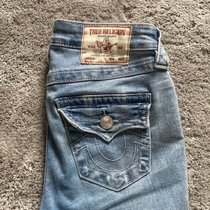 Ljusblå bootcut jeans från True Religion - Jag vill se hur mkt jag kan få för dom. Köpte dom för ca 2 månader sen och ör använda typ 10 ggr. De är i modellen BECCA mid Rise Bootcut i strl w24. Skriv för att ge pris förslag 