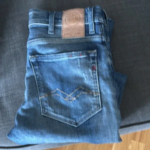Blå Replay jeansbyxor - Säljer ett par klassiska blå jeans från Replay med snygga slitningar och bra passform. Kan också köpa tre par jeans tillsammans. Tveka inte och höra av er över frågor!