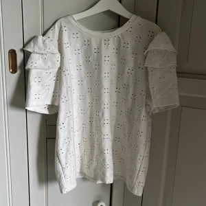 Vit blus med volangärmar från Zara - Säljer en söt vit blus från Zara med broderade hålmönster och volangdetaljer på ärmarna. Blusen har rund halsringning och korta ärmar med dubbla volanger, inga fläckar någonstans💞