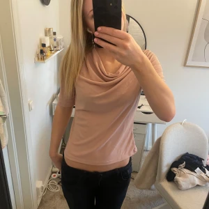 Ljusrosa topp - Säljer en ljusrosa topp från Stockh LM med draperad, vid halsringning och halvlånga ärmar. Toppen är i ett mjukt, stretchigt material och har en elegant, feminin look.