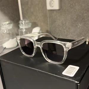 Transparenta solglasögon från Waye Vision - Stilrena solglasögon med transparent båge och svarta glas från Waye Vision. Skandinavisk design som ger en modern och fräsch look. Perfekta för soliga dagar och passar till de flesta outfits.