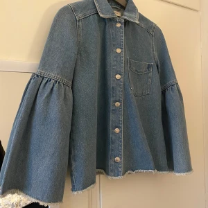 Jeansjacka med vida ärmar från NORR - Säljer en ljusblå jeansjacka från NORR med unika vida ärmar och råa kanter. Jackan har klassisk krage, bröstficka och knäppning framtill med metallknappar.  Använd fåtal gånger så är i mycket bra skick, ny pris 1 189kr🌸
