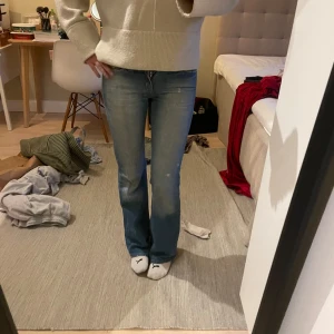 Ljusblå bootcut jeans - Säljer ett par ljusblå jeans från vintage Gina tricot med bootcut-passform. Jeansen har rosa/röda sömmar och den klassiska loggan på bakfickan. Perfekta för dig som gillar en avslappnad men ändå snygg stil.