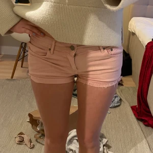 Ljusrosa jeansshorts - Säljer ett par ljusrosa jeansshorts med råa franskantsdetaljer. Shortsen har klassisk femficksdesign, bälteshällor och knappgylf. Perfekta för varma dagar och enkel att matcha med olika toppar. Har en liten fläck där bak men syns knappt och går säkert bort i tvätten❤️❤️