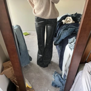 Svarta skinnbyxor bootcut - Säljer ett par svarta skinnbyxor med bootcut-modell. Byxorna har hög midja och klassisk femficksdesign. Snyggt glansigt material som ger en cool look. Perfekta till en stickad tröja eller t-shirt.
