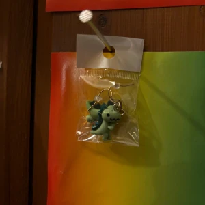Dinosaurie örhängen i grönt - Säljer ett par söta örhängen med små gröna dinosaurier som hänge. Perfekta för dig som gillar roliga och unika accessoarer. Fästs med klassisk krok.