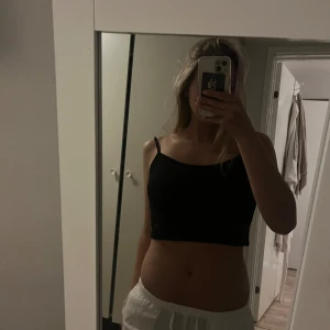 Svart croppad linnetopp - Säljer en enkel och stilren svart croppad linnetopp med tunna axelband. Perfekt för varma dagar eller att styla lager på lager. Toppen har en rak passform och har en öppen rygg.