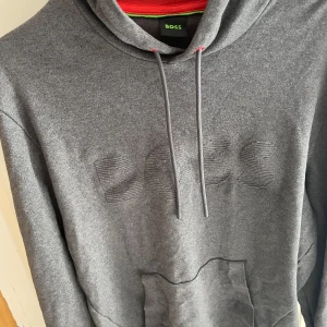 Hugo boss hoddie  - Säljer en stilren grå hoodie från BOSS med broderad logga framtill. Använd max 2-3 gånger. Ny pris ligger runt 1200. Skriv vid funderingar!