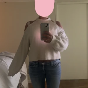 Beige croppad stickad tröja offshoulder - Säljer en beige croppad stickad tröja med offshoulder-detalj och lång ärm. Tröjan har en högre halsringning och är perfekt för dig som gillar en chill men trendig look. Passar snyggt till både jeans och kjol.