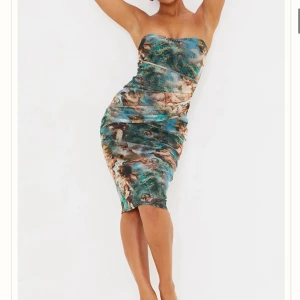 Multi Renaissance Print Mesh Bandeau Drape Midi Dress (PrettyLittleThing) - Säljer en tight, axelbandslös tubklänning från PrettyLittleThing i mycket bra skick. Klänningen har ett unikt konstinspirerat mönster i blågrönt och beige, med figurnära passform som framhäver kroppen. Den är kort och sitter snyggt – perfekt för utekvällar, dejt eller fest. En klänning för dig som vill sticka ut med en trendig och konstnärlig look!