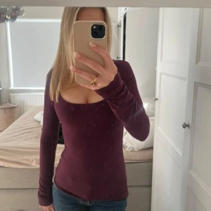 Vinröd långärmad topp med fyrkantig ringning - Säljer en vinröd långärmad topp med snygg fyrkantig ringning. Modellen är tight och sitter figurnära, perfekt till jeans eller kjol. Materialet känns mjukt och stretchigt, troligtvis bomull eller polyester. Enkel och stilren design utan mönster eller detaljer.