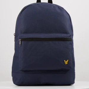 Mörkblå ryggsäck från Lyle & Scott - Snygg och stilren mörkblå ryggsäck från Lyle & Scott med klassisk gul logga framtill. Väskan har ett stort huvudfack, en praktisk ytterficka med dragkedja och svarta justerbara axelband. Perfekt för skolan eller stan.