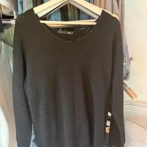 Svart stickad tröja från 157 XS - En svart stickad tröja från 157 i storlek XS. Tröjan har en enkel och clean design med rund halsringning och långa ärmar. Perfekt att matcha med jeans eller kjol för en chill look. 