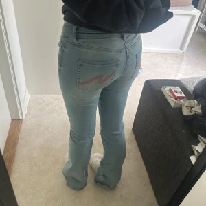 Ljusblå bootcut jeans från Nelly - Säljer nu dessa populära Nelly jeansen med fina rosa detaljer på bakfickorna. Inte speciellt mycket använda så i bra skick förutom längst ner på benen där de är lite skadat som syns på bild 5. Men skulle säga att det inte är något man märker av. Nypris är 699kr säljer för 400kr🥰