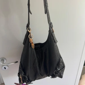 Svart axelväska - Cool svart axelväska, använd men som i nyckick. Rymmer en liten macbook. Köpt för 600kr.