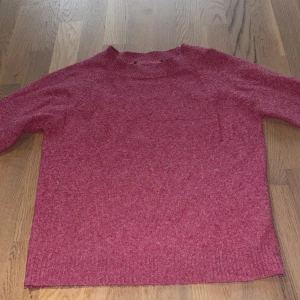Rosa stickad tröja från Vero Moda - Mysig rosa stickad tröja med rund halsringning och långa ärmar. Tröjan har en enkel design med ribbade muddar vid hals och nederkant. Tröjan är från Veromoda💓