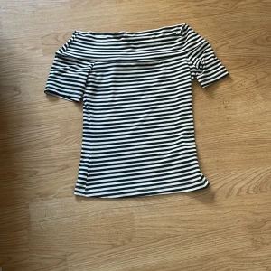 Randig offshoulder topp från H&M XS - Säljer en svartvit randig offshoulder topp från H&M i storlek XS. Toppen har korta ärmar och en tight passform som sitter snyggt över axlarna. Perfekt för dig som gillar en stilren och trendig look.