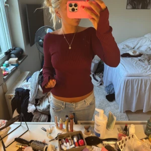 Vinröd ribbad långärmad topp - Säljer en vinröd, ribbad långärmad topp med offshoulder-skärning. Tröjan har en tight passform och är tillverkad i ett stretchigt material som sitter snyggt på kroppen. Perfekt att styla med jeans eller kjol för en trendig look.