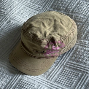 y2k keps  - Snygg beige keps från Esprit med rosa tryck och broderade detaljer. Kepsen har en klassisk form med böjd skärm, justerbar rem baktill och coola ventilationshål på sidorna. Perfekt accessoar för en avslappnad streetstyle-look.
