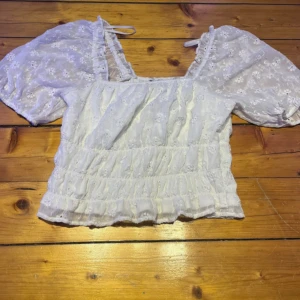 Vit blus med puffärm från Vero Moda - Supersöt vit blus från Vero Moda med broderade blommor och puffiga korta ärmar. I storlek S aldrig använd 