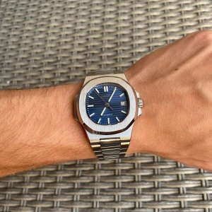 Seiko automatisk klocka blå urtavla - Snygg Seiko automatisk klocka med blå urtavla och datumvisning. Boetten är åttakantig i silverfärgat stål och armbandet är robust i matchande metall. Urtavlan har subtila vågmönster och tydliga indexmarkeringar. Perfekt accessoar för dig som gillar stilren design.