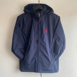 Ralph lauren regnjacka - Riktigt fet Ralph Lauren regnjacka. Använd fåtal gånger under våren men har inga defekter. Jackan tillkommer med luva som man kan välja att använda eller gömma. Jackan är i storlek M, passar även storlek S och L. Om ni har några övriga frågor så är det bara att skriva💫