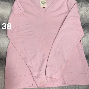 Ljusrosa v-ringad tröja  - Söt ljusrosa v-ringad tröja. Tröjan har lång ärm och en klassisk passform som funkar till många olika stilar. Perfekt för dig som gillar en enkel men fräsch look.🌸Fläckar. Storlek 38