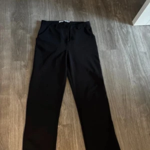 Svarta raka kostymbyxor - Snygga svarta kostymbyxor med rak passform och klassisk look. Perfekta till en stilren outfit och passar lika bra med sneakers som med boots. Byxorna har enkel design utan synliga detaljer och är riktigt lätta att matcha.