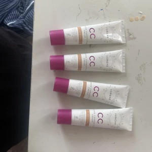 Lumene CC Cream Medium x4 - Fyra tuber Lumene CC Color Correcting Cream i nyansen Medium. Tuben är vit med lila lock och guldiga detaljer. Ger en jämn och naturlig finish, perfekt för att jämna ut hudtonen. Lätt krämig formula som smälter in i huden.
