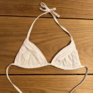 Vit bikiniöverdel från Calzedonia - Snygg vit trekantsbikini från Calzedonia med knyt i nacken och ryggen. Klassisk modell med lätt rynkade kupor och tunna band. Materialet är mjukt och följsamt syntet. Den är storlek S och har blivit för liten för mig, och det är därför jag nu säljer den. Endast använd en gång. 💖