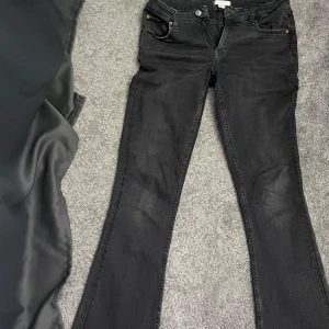 Svarta bootcut jeans Gina Tricot - Snygga svarta jeans från Gina Tricot med bootcut-modell. Jeansen har klassisk femficksdesign, svarta sömmar och en lätt tvättad look.