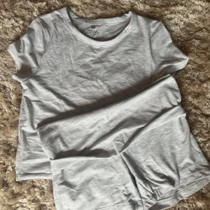 Ljusgrå t-shirt och shorts från H&M - En basic ljusgrå t-shirt och shorts från H&M i mjuk bomull. T-shirten har rund halsringning och korta ärmar, perfekt för en clean och enkel stil. Passar till allt och är superbekväm att bära. Mjukis sett typ från hm jag aldrig använt 🤍