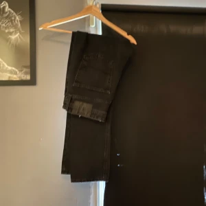 Svarta jeans från Jack & Jones - Säljer ett par svarta jeans från Jack & Jones. Klassisk femficksmodell med raka ben och normal passform. Jeansen är tillverkade i bomull och har en stilren look som funkar till det mesta. Perfekta för dig som gillar enkel och tidlös stil.