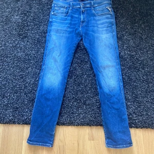 Blå Replay Hyperflex jeans - Säljer ett par blå Replay Hyperflex jeans med klassisk femficksdesign. Jeansen har raka ben och normal passform, tillverkade i stretchigt denim för extra komfort. Perfekta för dig som gillar en stilren och avslappnad look.